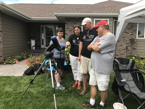 Friends and fellow travel bloggers look at the eclipse through a telescope in our front yard.