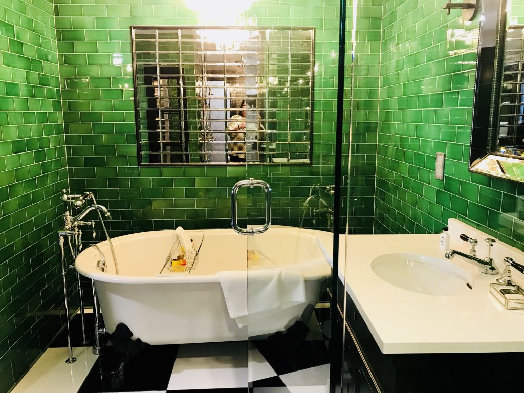 This emerald green bathroom has a large clawfoot tub in addition to a walk in shower with floating glass doors.